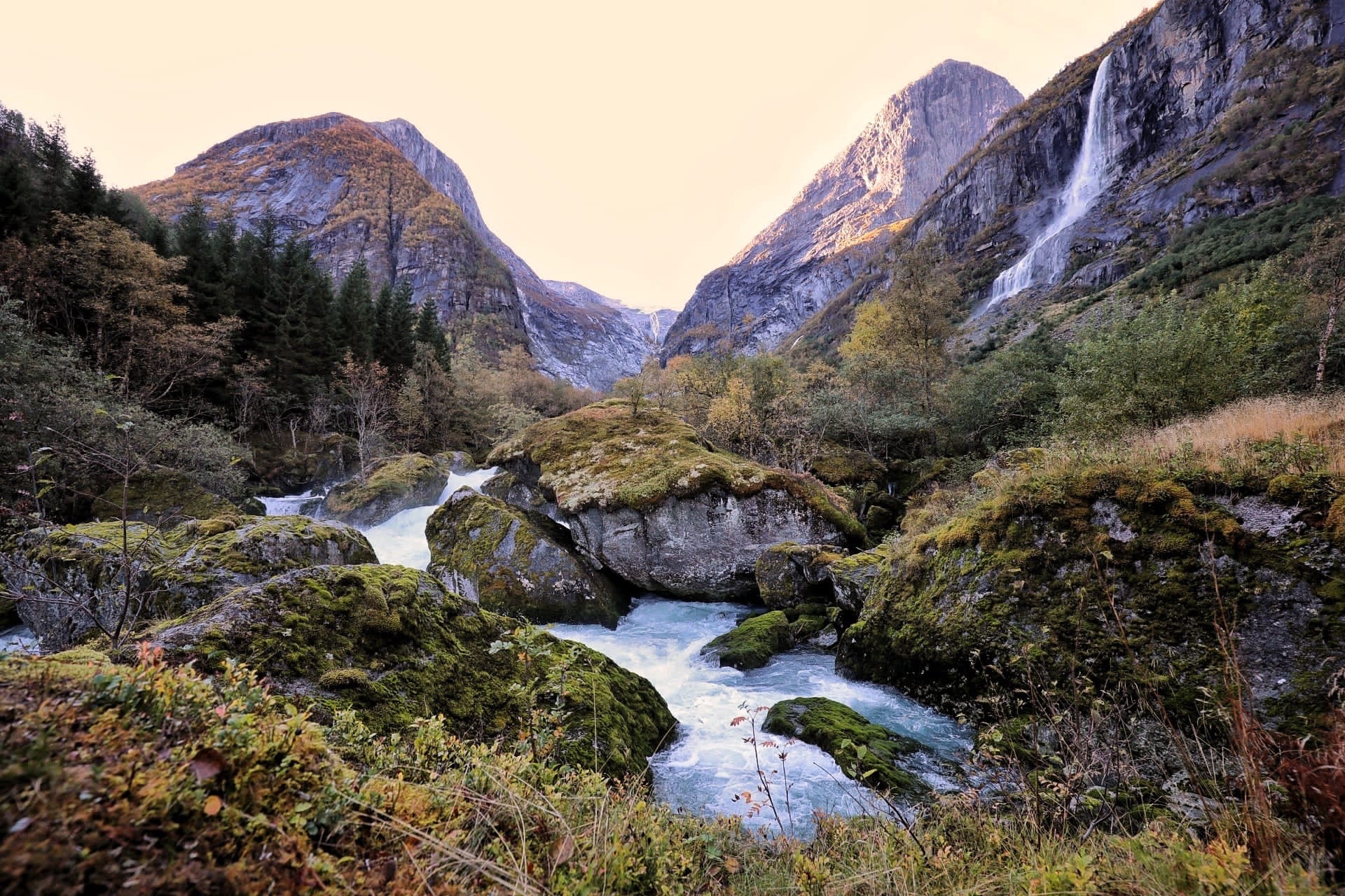 Waterval en rivier in een rotsachtige bergvallei.